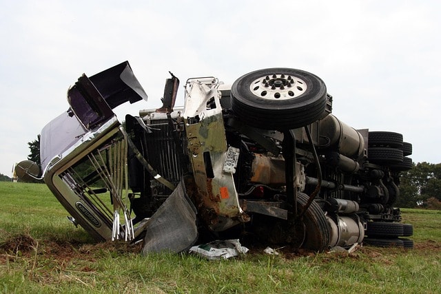 Overturned commercial truck on grassy field, illustrating the aftermath of a trucking accident related to wrongful death claims in Alabama.